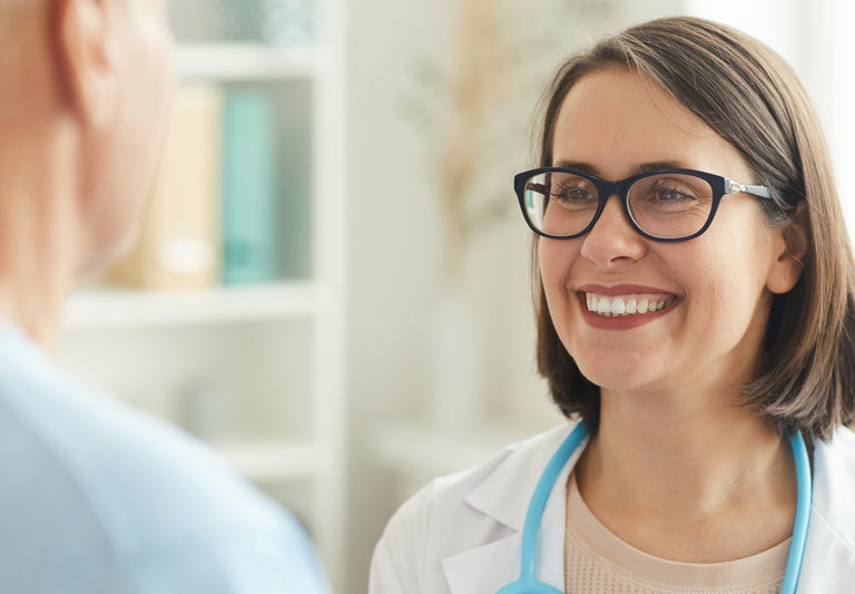Smiling Female Doctor Looking At Senior Patient