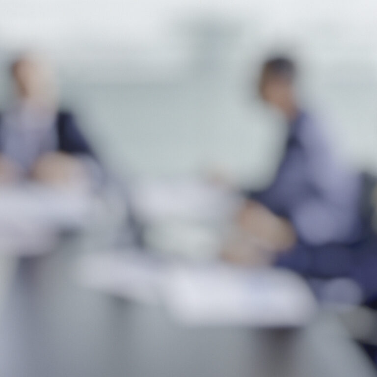 Defocused shot of business team at the meeting, purposely blurred with a lens, copy space.